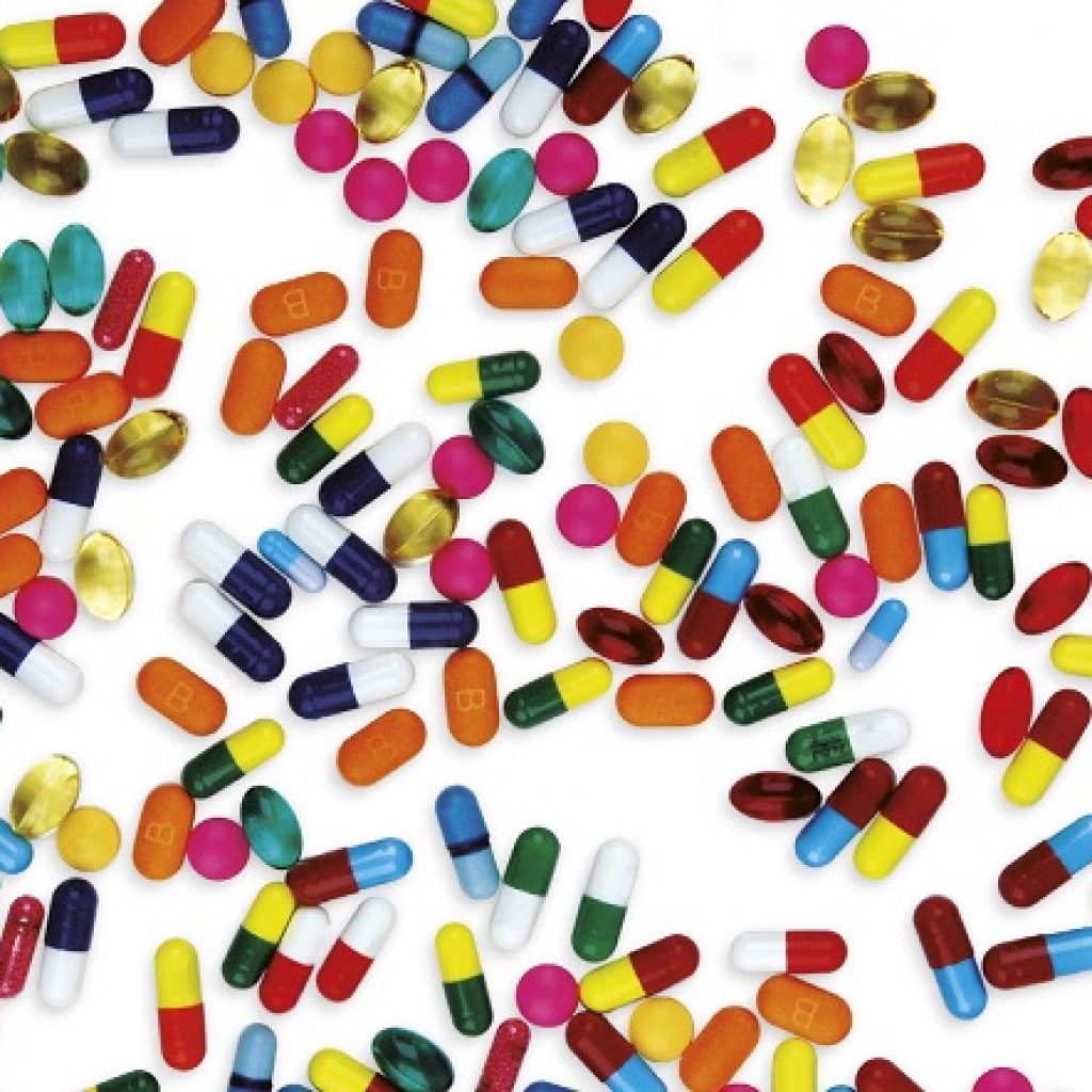 Multiple coloured pills on a white background