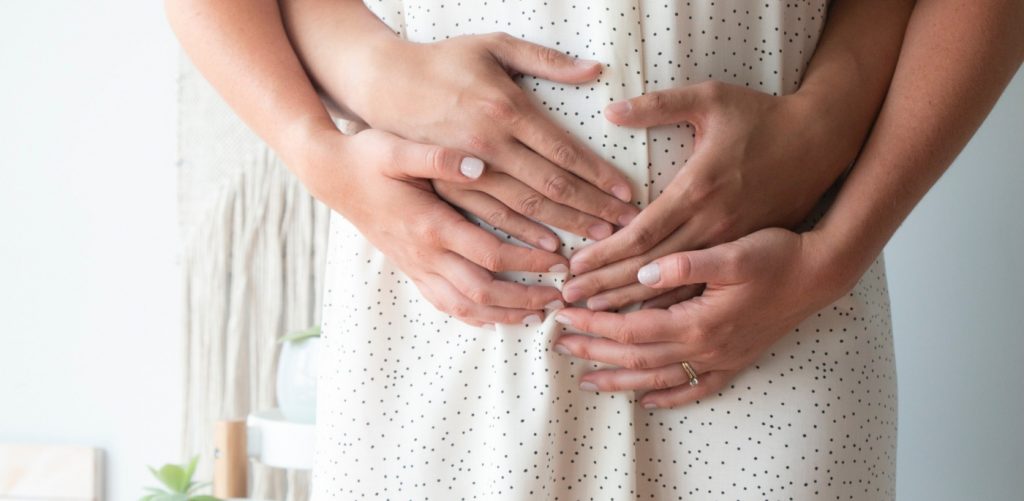 4 Hands on a pregnant woman's belly