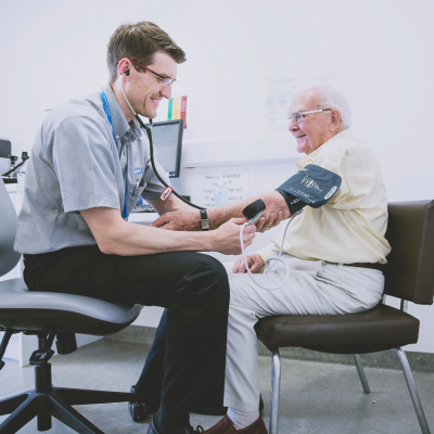 Doctor taking an older person's blood pressure.